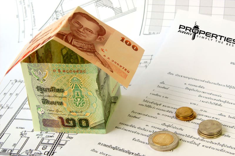 Thai baht banknotes folded into the shape of a small house, standing on paperwork next to a stack of coins, symbolic image for money and banking in Thailand