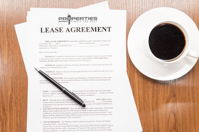 A printed lease agreement document with a pen and a cup of coffee on a wooden desk